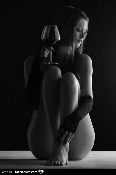Ragazza seminuda beve vino rosso