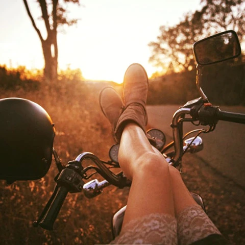 Gambe di ragazza sopra il manubrio della motocicletta